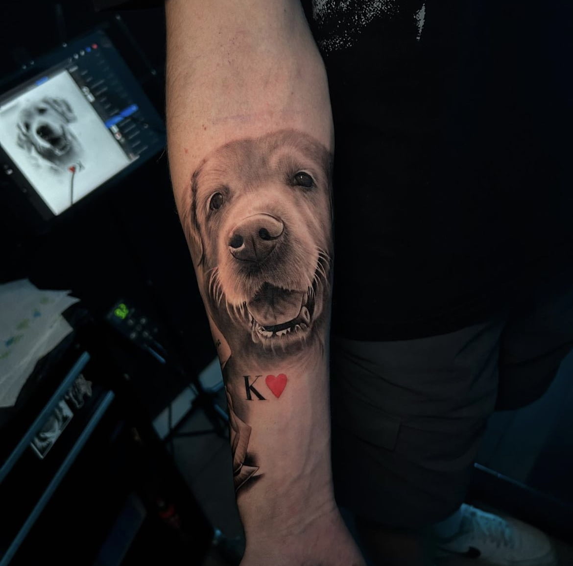 Retrato de perro estilo realista en antebrazo con detalle de K y corazón.