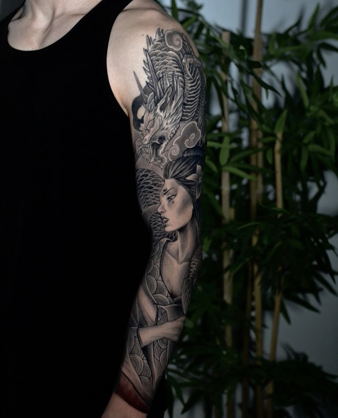 Tatuaje de dragón japonés con figura femenina en estilo realista en el brazo, transmitiendo fuerza y misticismo.