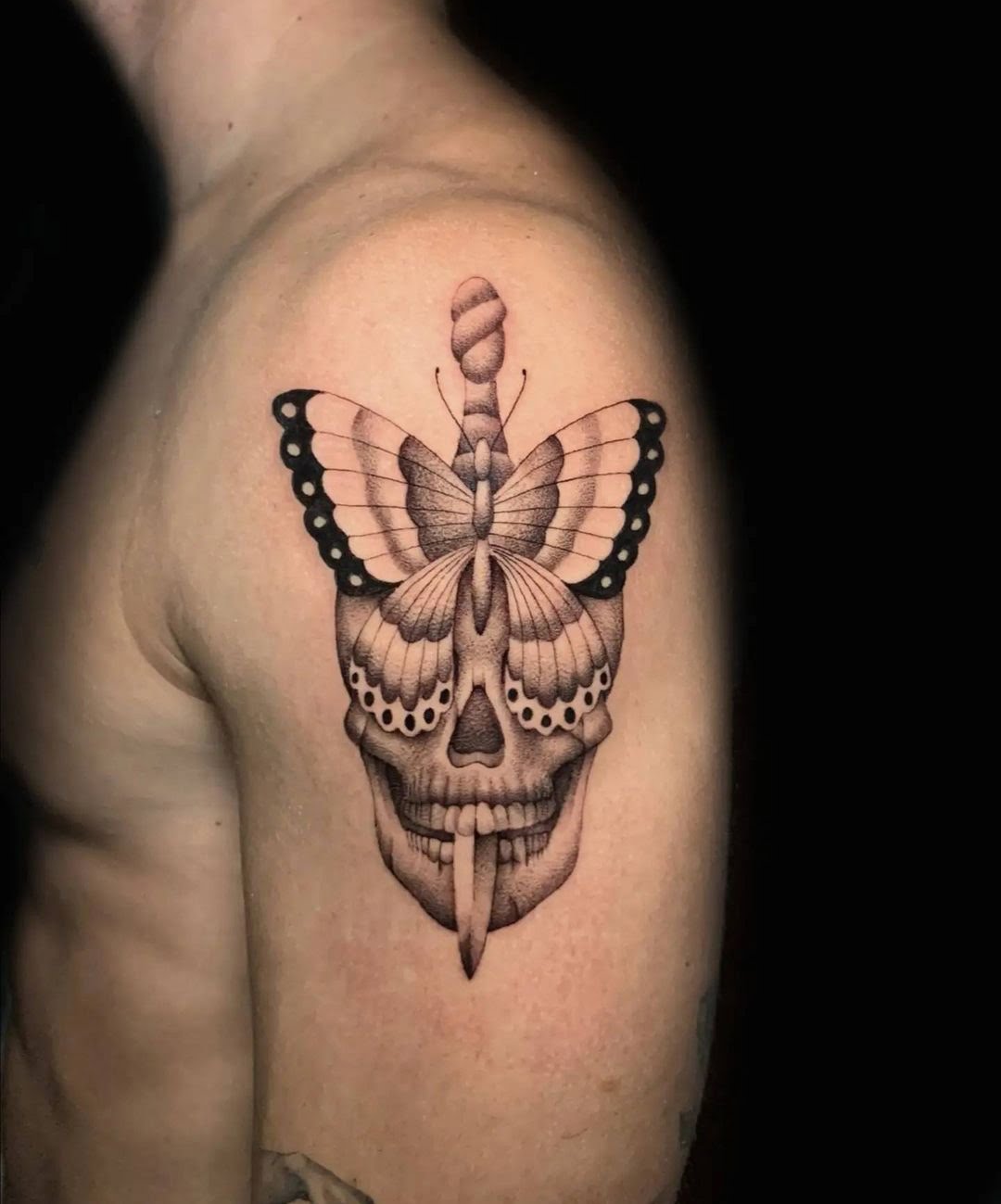 Tatuaje blackwork de calavera y mariposa en el brazo, estilo surrealista con sombreado intricate.