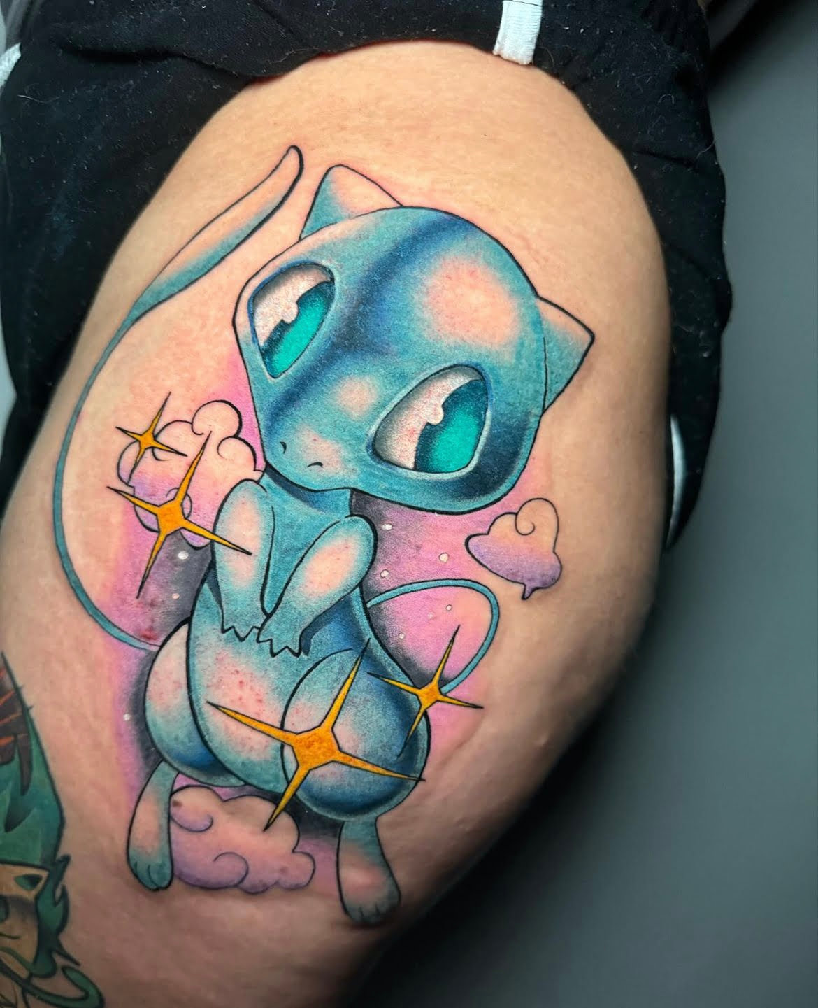 Tatuaje de Mew en estilo neotradicional con tonos pastel en el muslo, transmitiendo fantasía y ternura.