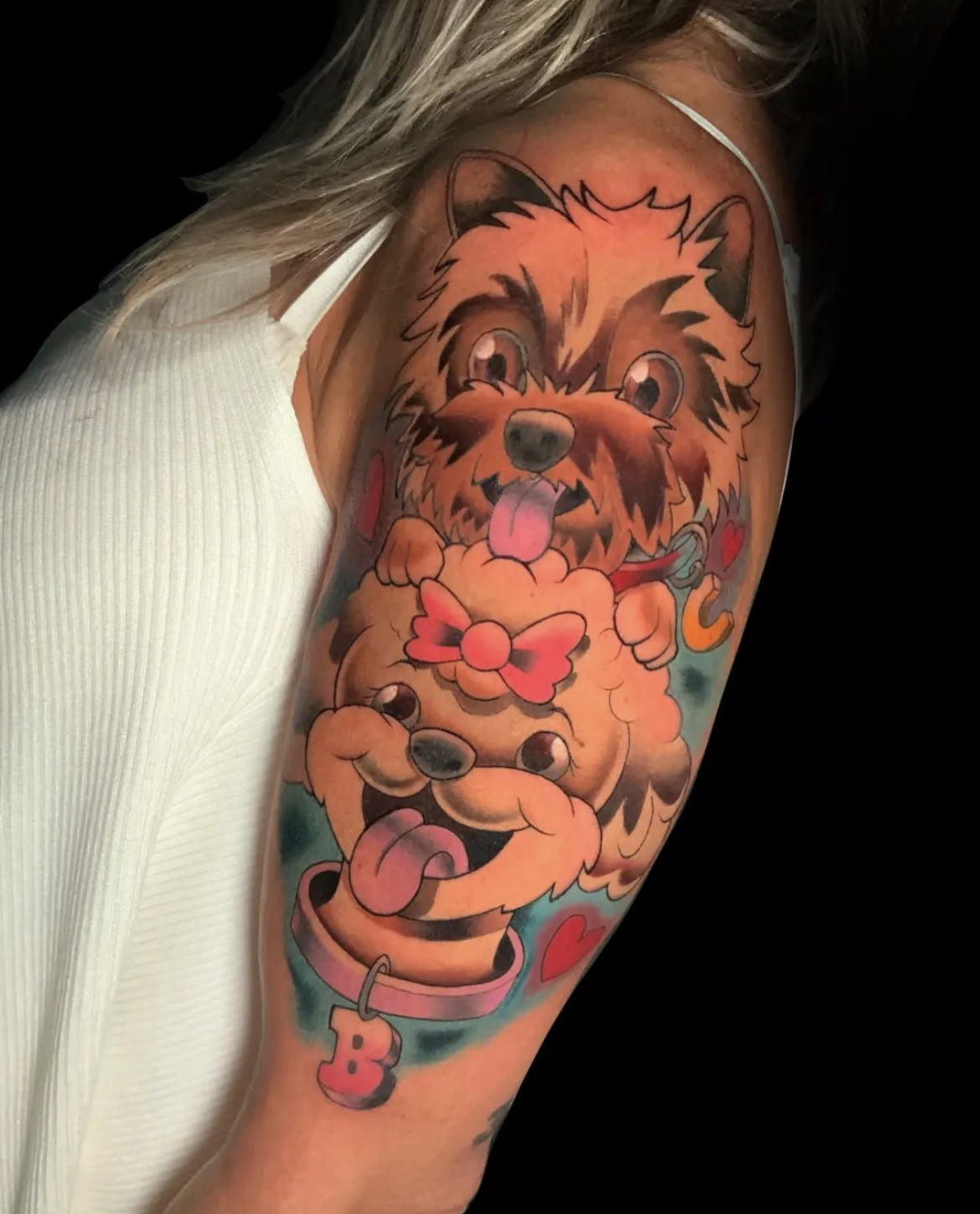 Tatuaje neotradicional de dos perros en el brazo con colores vivos y detalles alegres.