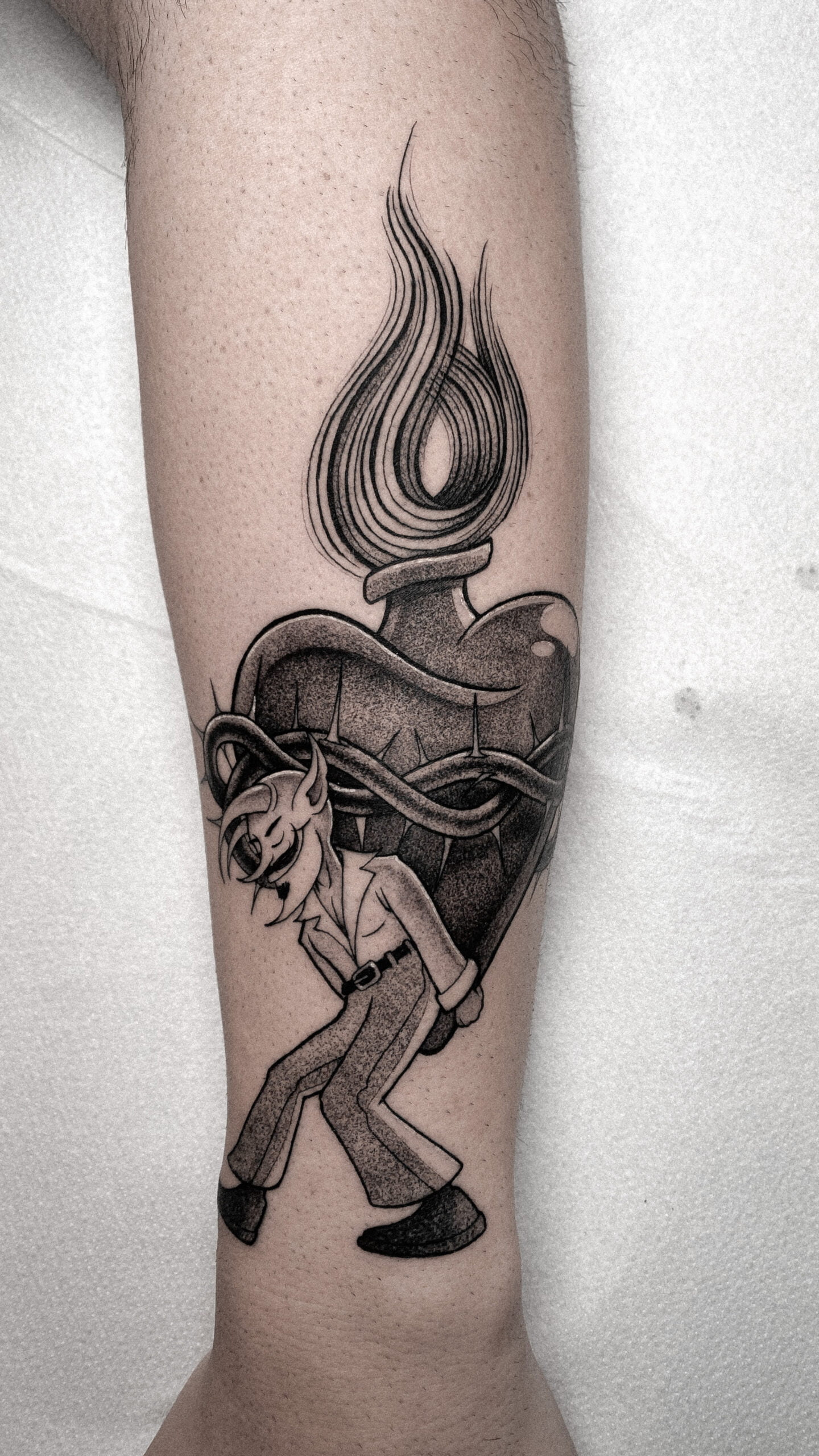 Tatuaje blackwork en el brazo de un corazón ardiente y figura animada, estilo surrealista.
