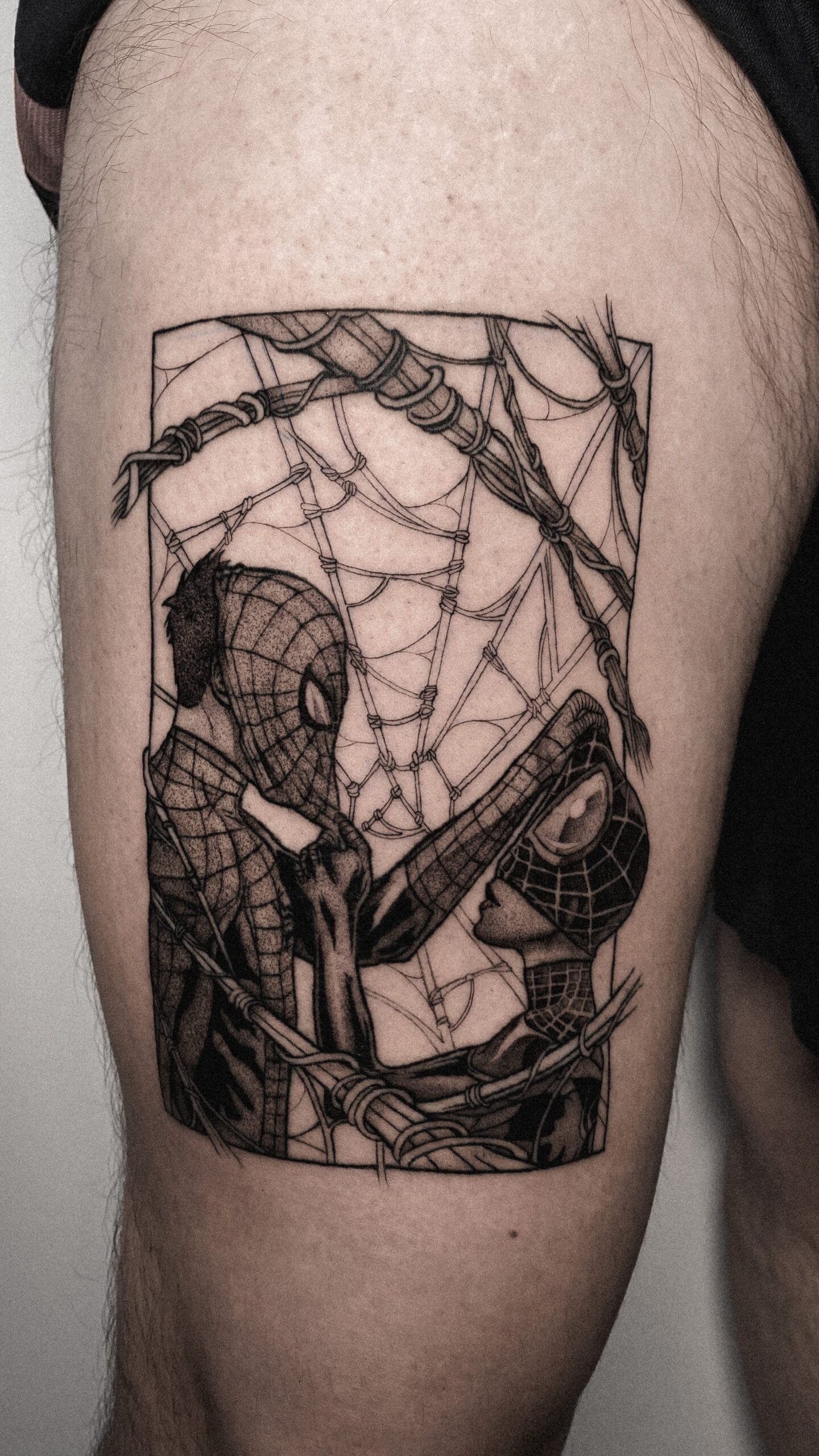 Tatuaje en estilo blackwork de Spider-Man y otro personaje en el muslo, usando líneas gruesas y sombreado artístico.