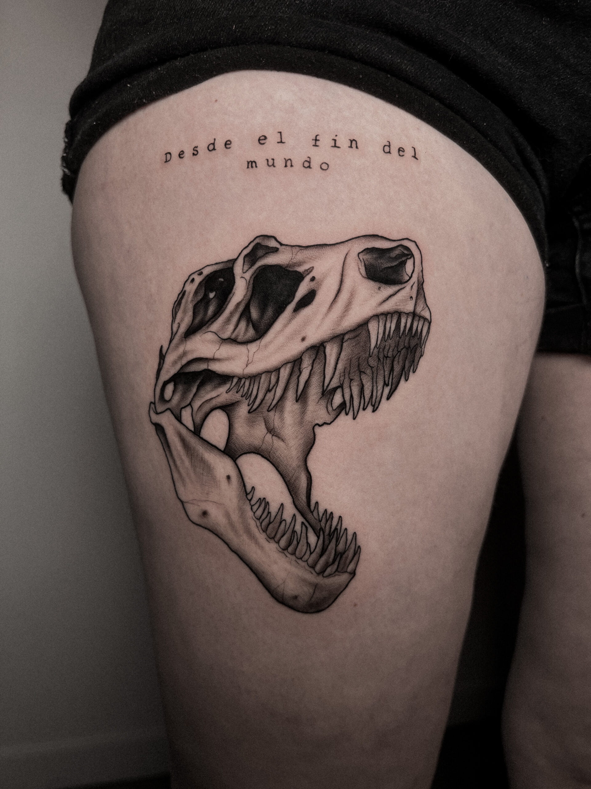 Cráneo de T-Rex en estilo blackwork con sombreado en muslo, transmitiendo fuerza.