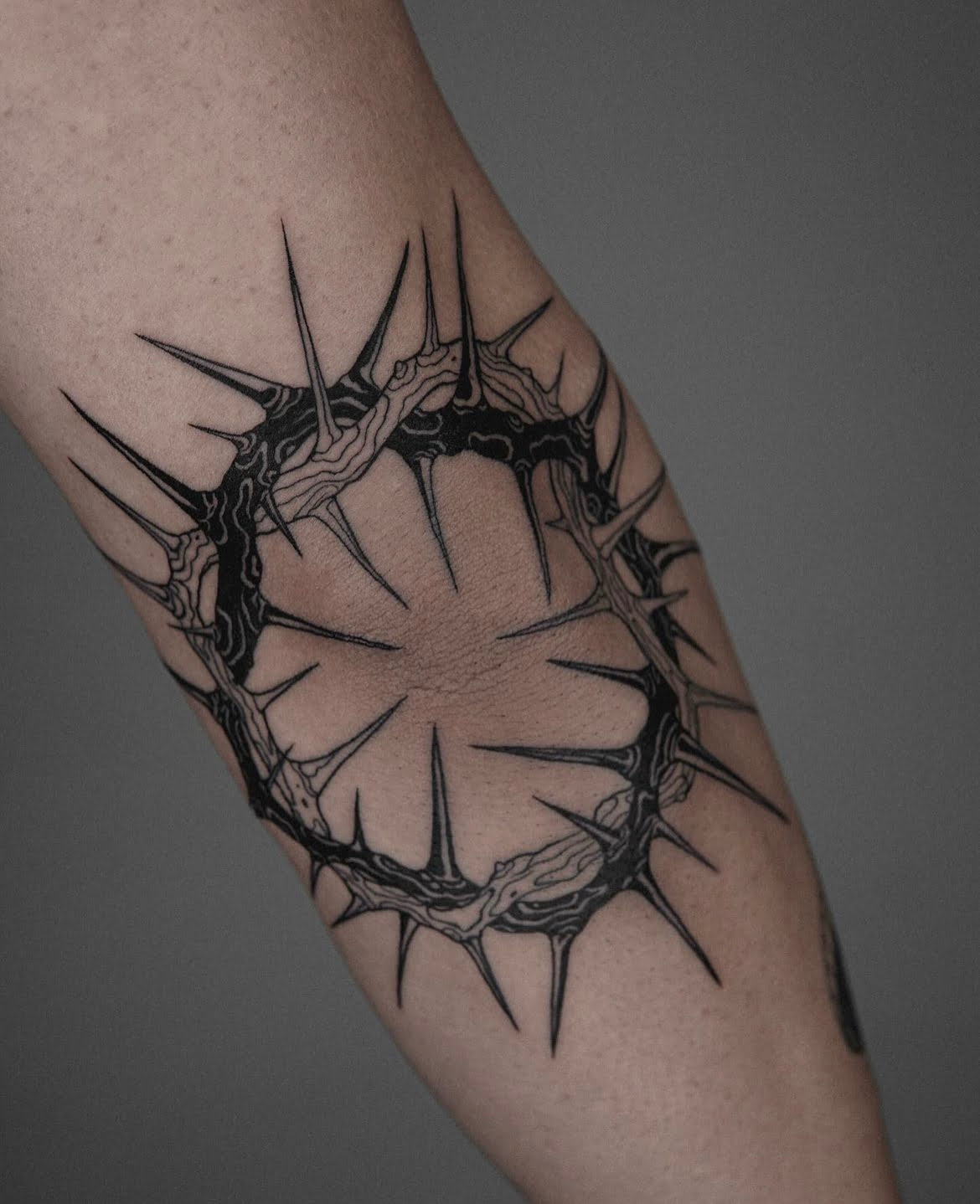 Tatuaje de espinas en estilo blackwork en el brazo, con líneas finas y diseño orgánico.