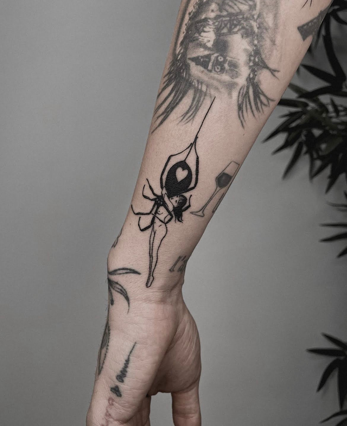 Tatuaje de estilo fineline con una figura de mujer y corazón en antebrazo.