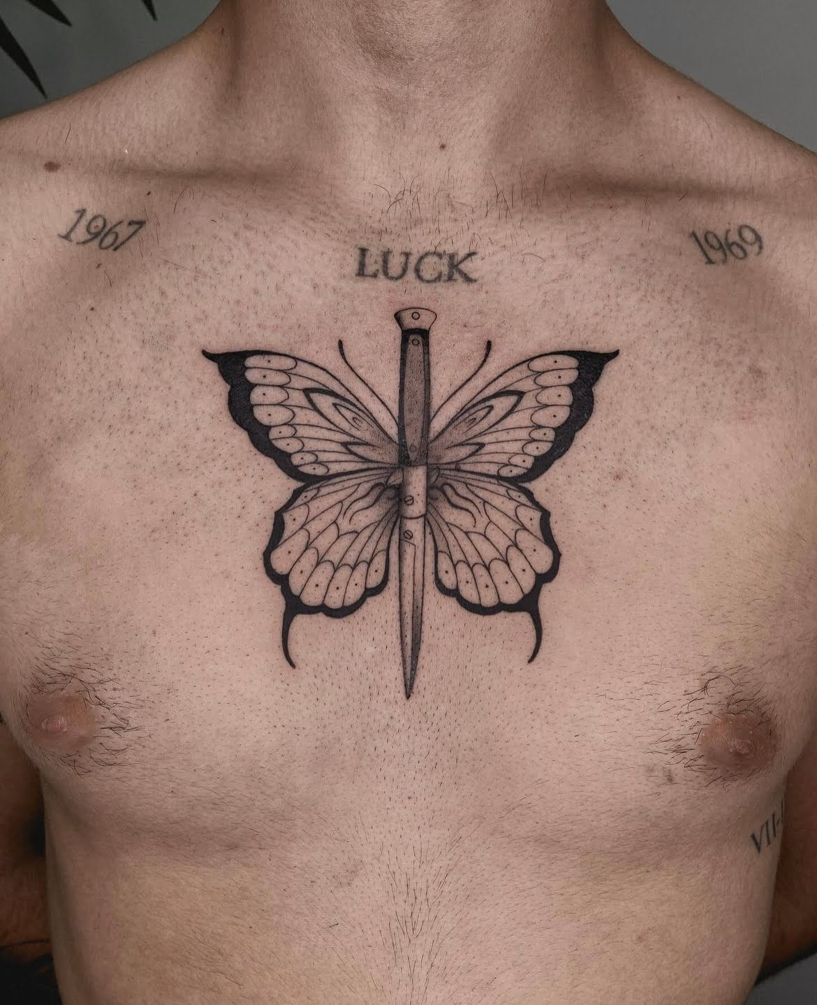 Tatuaje de mariposa con daga estilo blackwork en el pecho, transmitiendo dualidad.