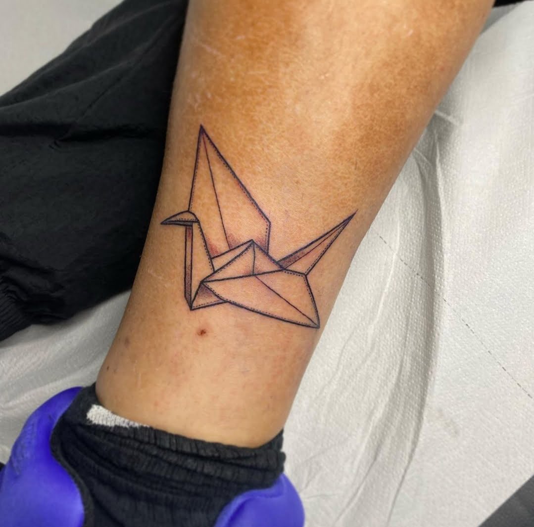 Tatuaje de una grulla en estilo lineal minimalista en la pierna