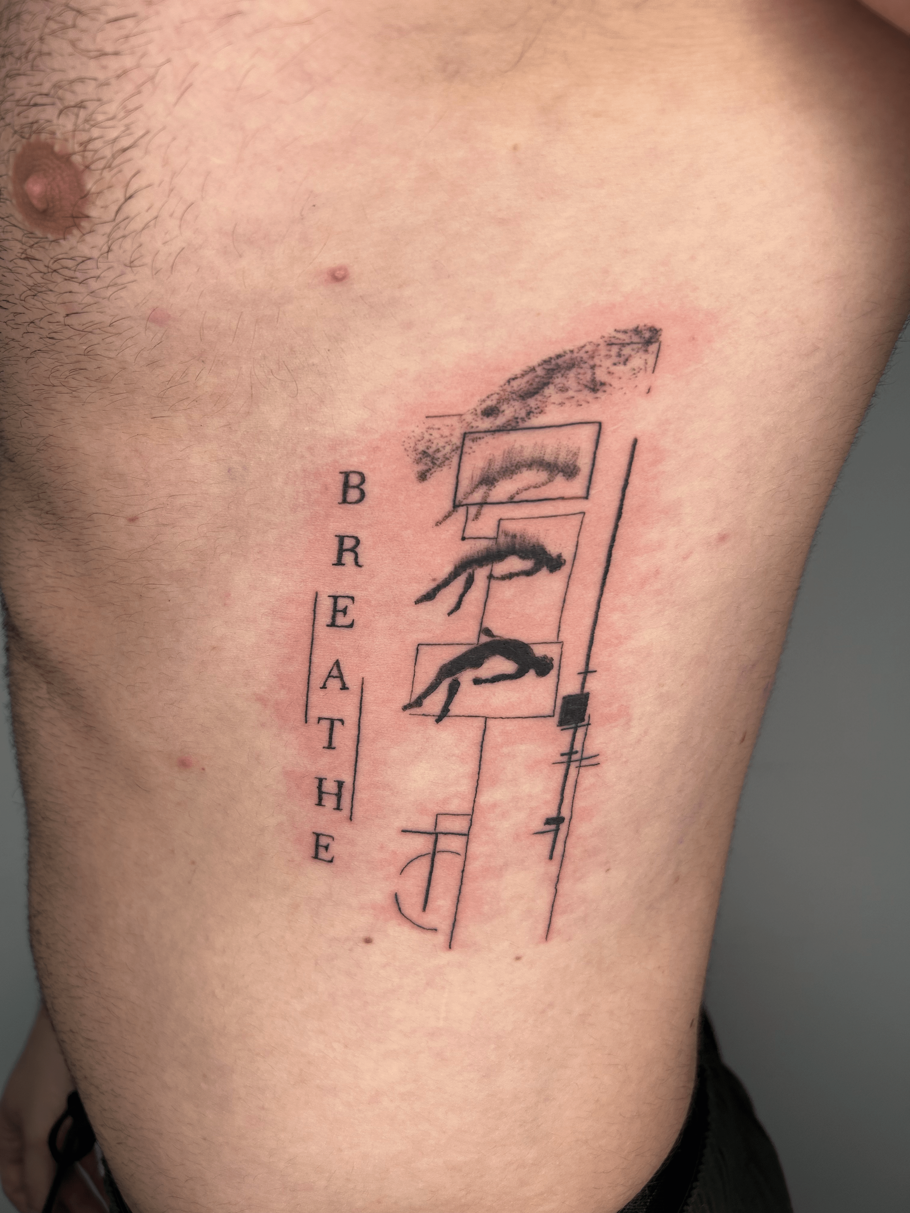 Tatuaje minimalista con texto 'Breathe' en el costado, líneas finas y detalles abstractos.