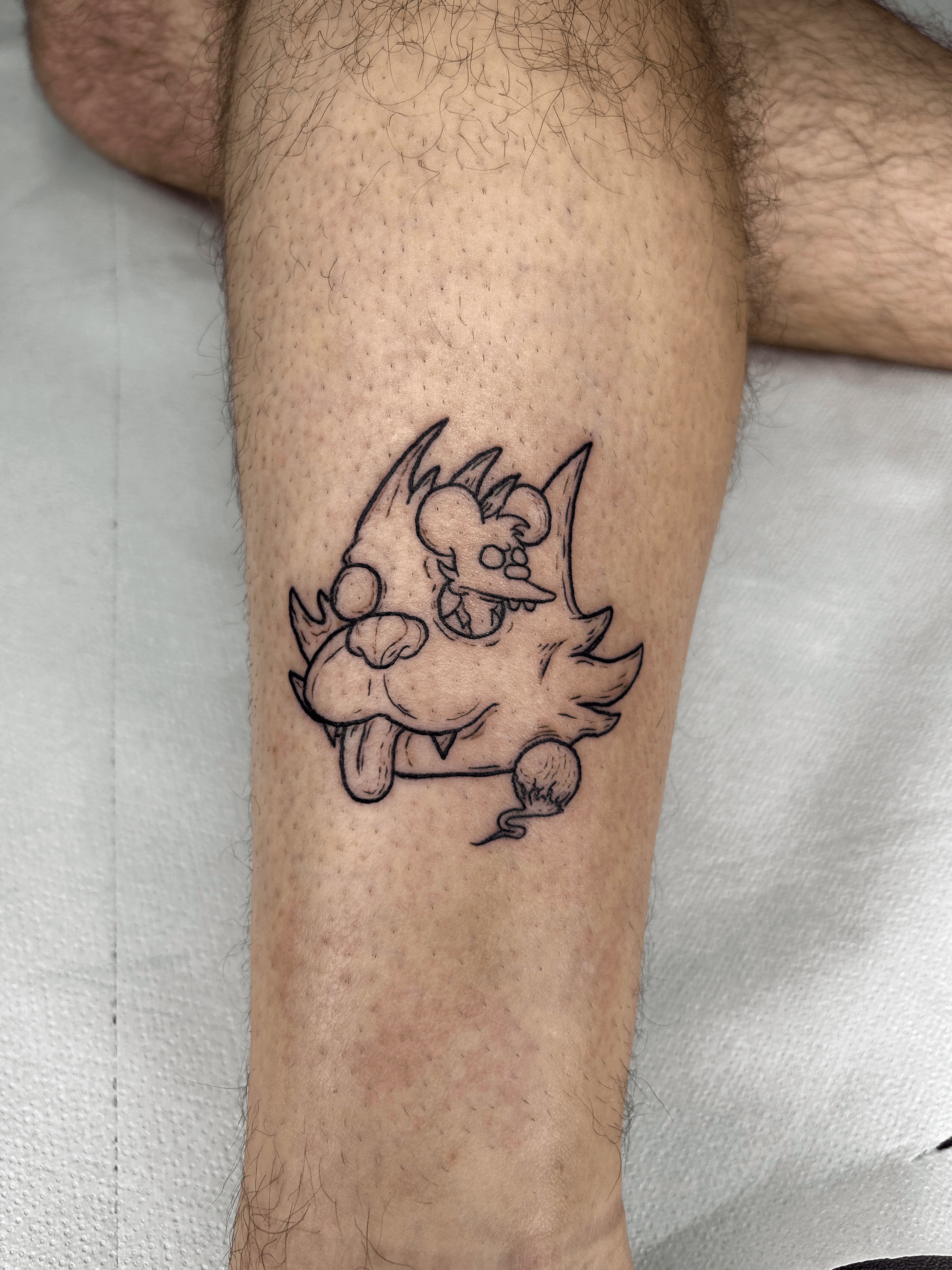 Tatuaje minimalista de un personaje caricaturesco en la pierna con líneas finas.