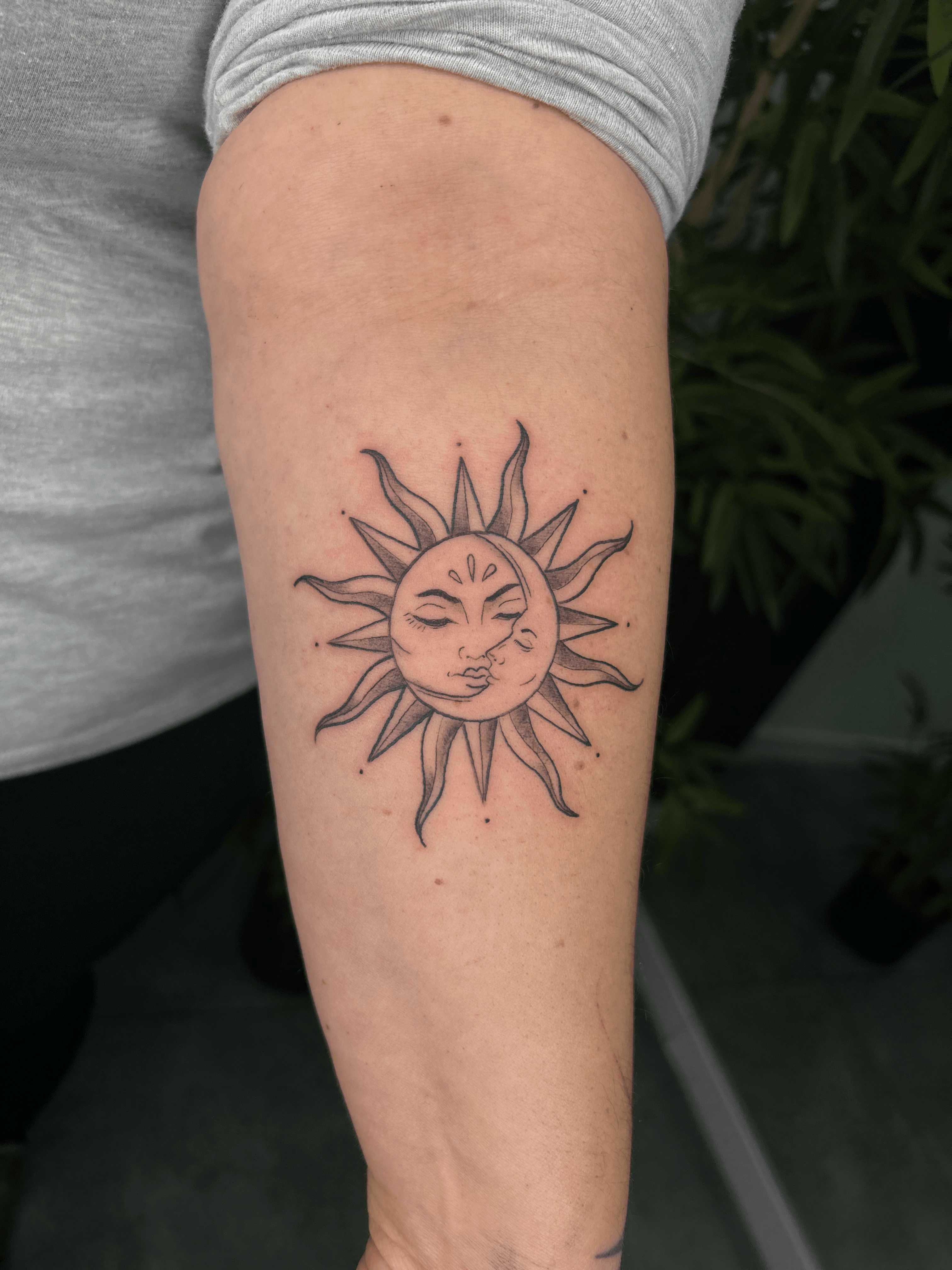 Tatuaje de sol y luna en estilo fineline en el antebrazo