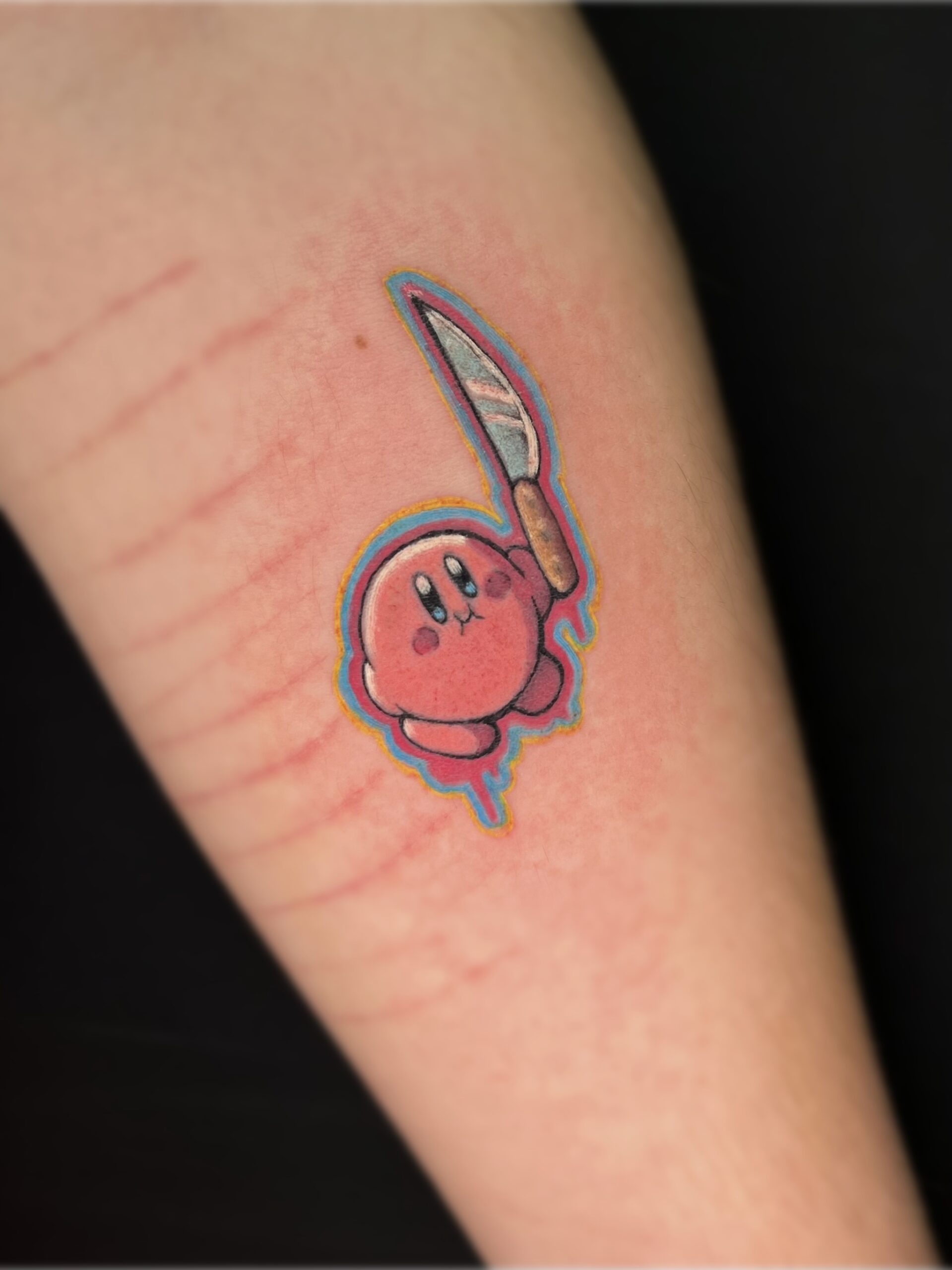 Tatuaje colorido de personaje animado con cuchillo, estilo neotradicional en el brazo.