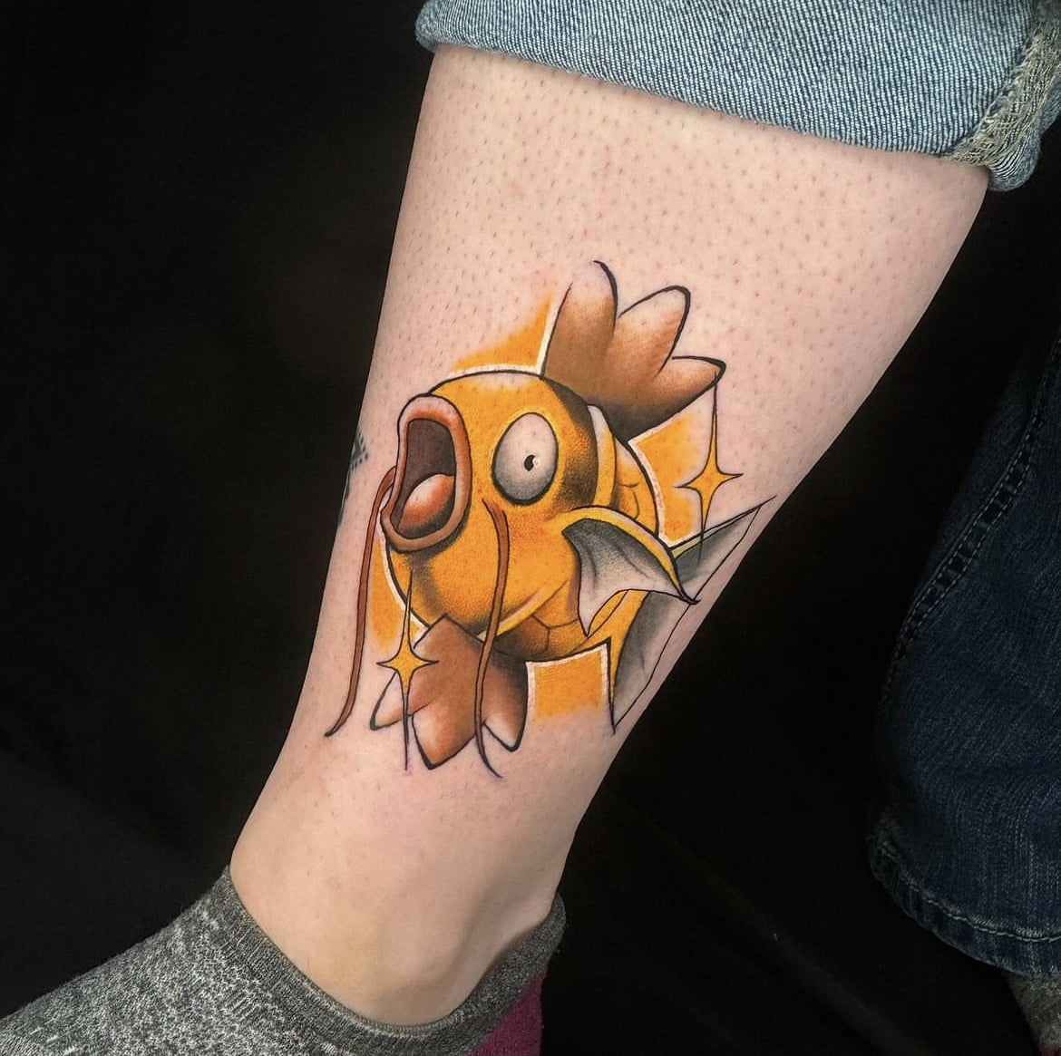 Tatuaje de Magikarp en estilo neotradicional con colores vibrantes en la pierna.