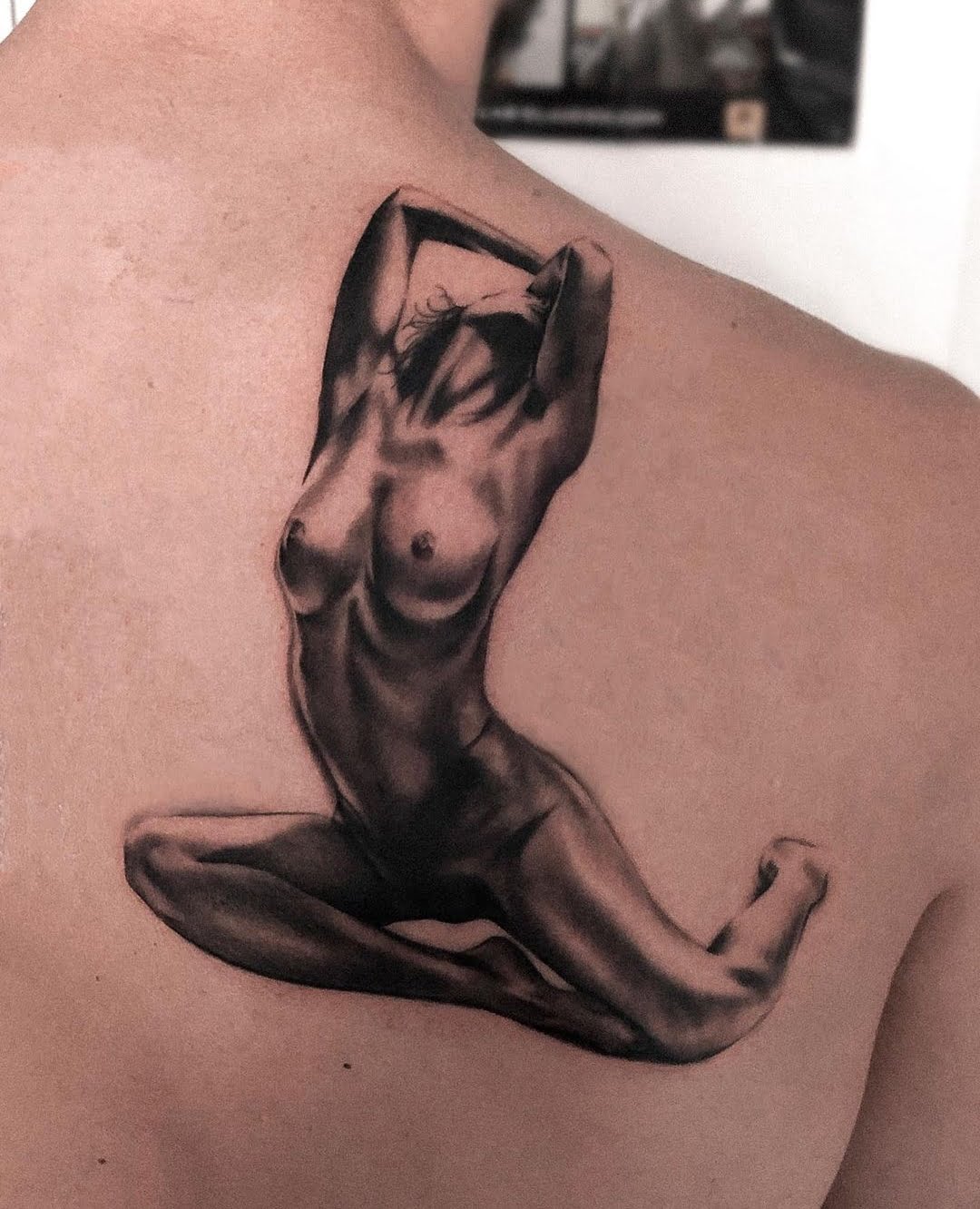 Tatuaje de figura femenina en estilo realista con sombreado en la espalda, transmitiendo serenidad.