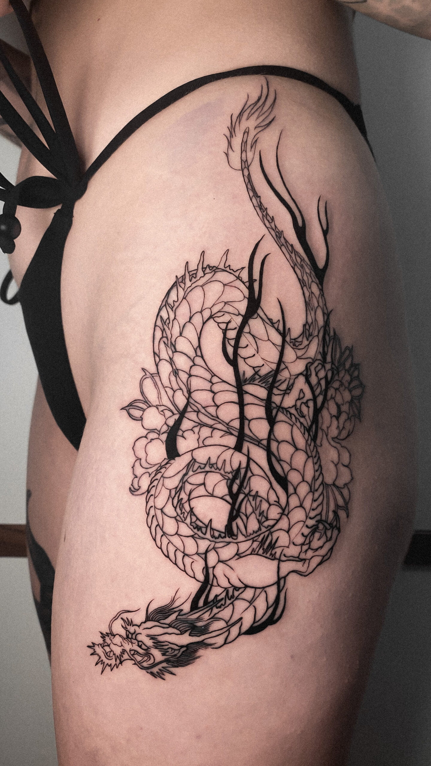 Tatuaje blackwork de un dragón japonés en la cadera.
