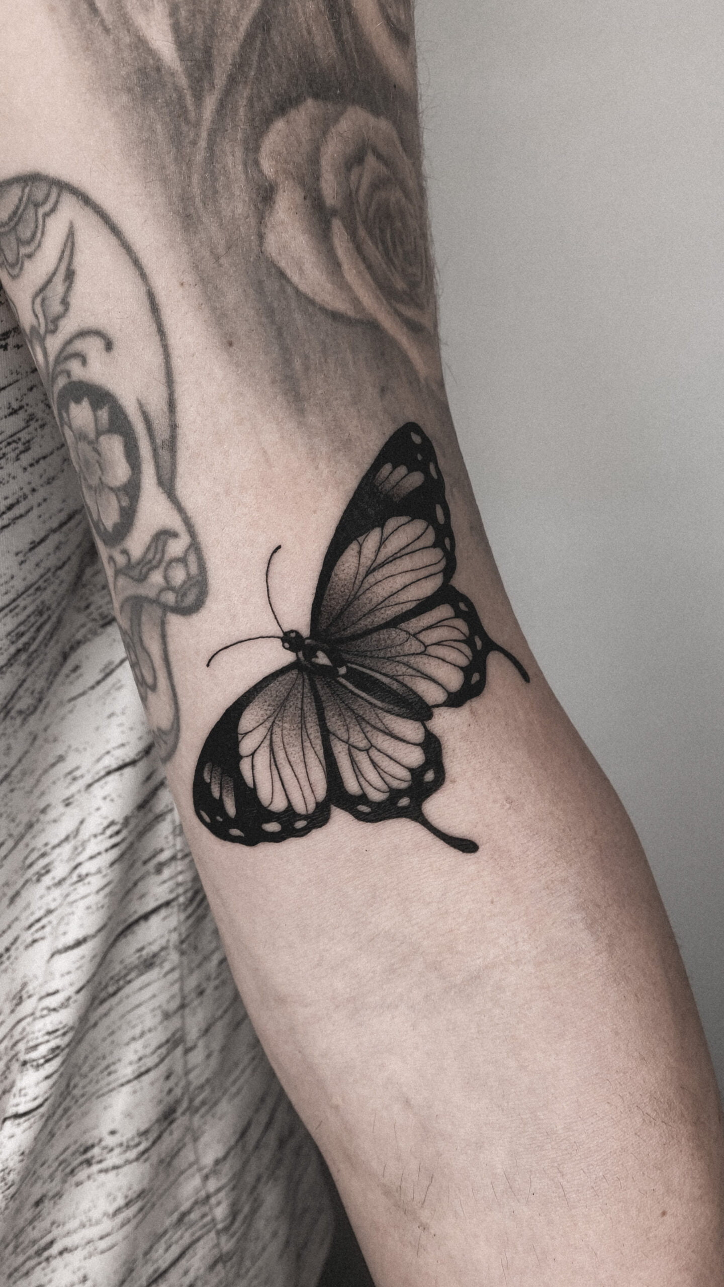 Tatuaje blackwork de una mariposa en el antebrazo.