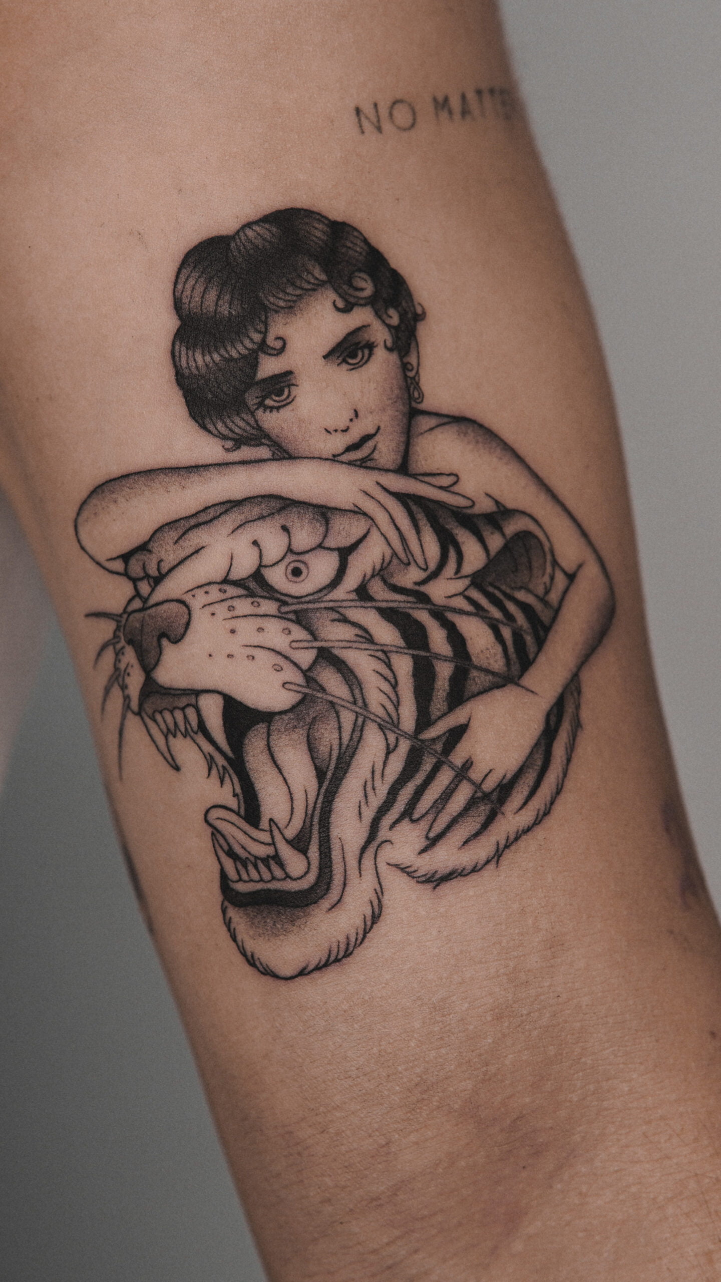 Tatuaje blackwork de una mujer abrazando a un tigre en el brazo.