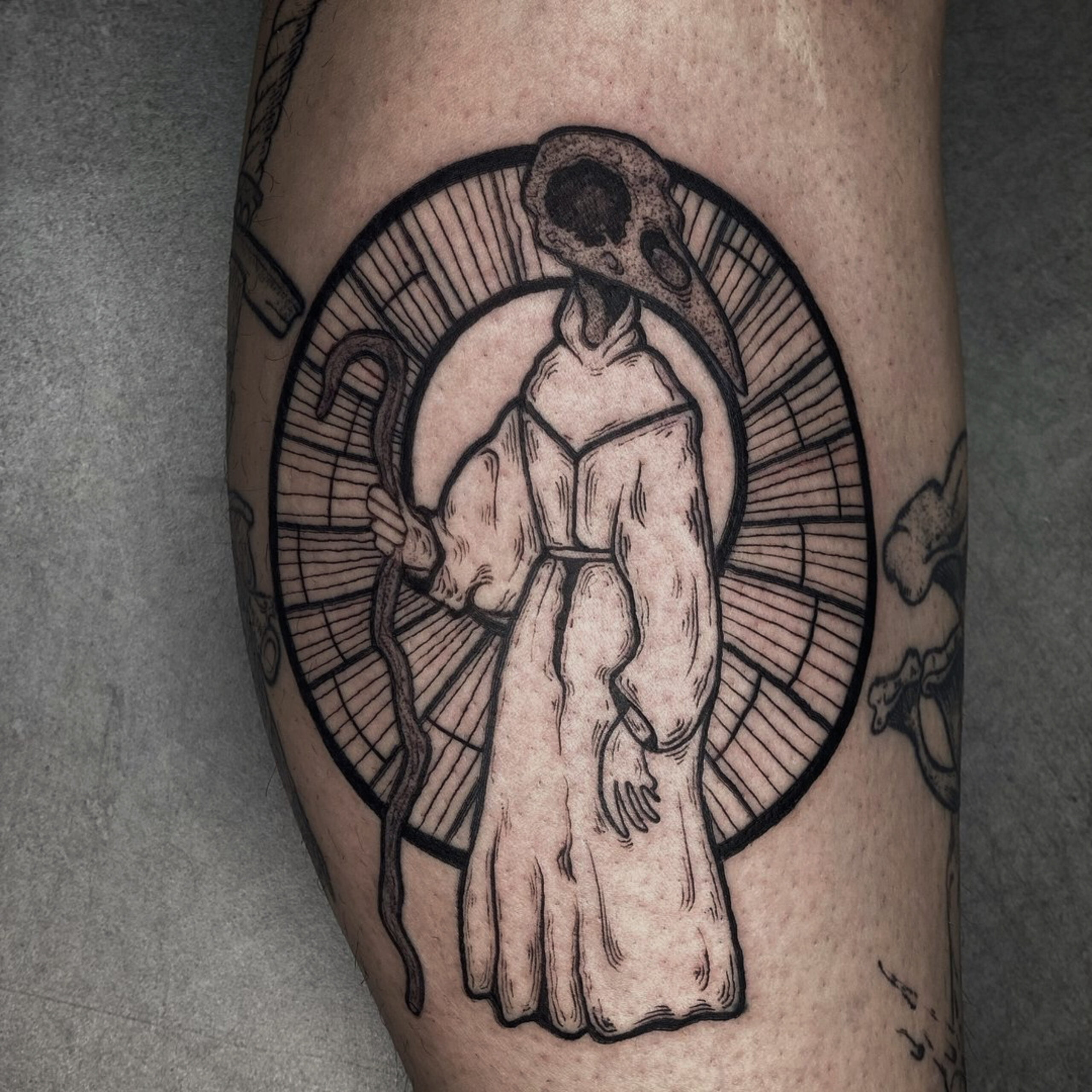 Figura con cabeza de cráneo de ave en estilo blackwork, en la pantorrilla.