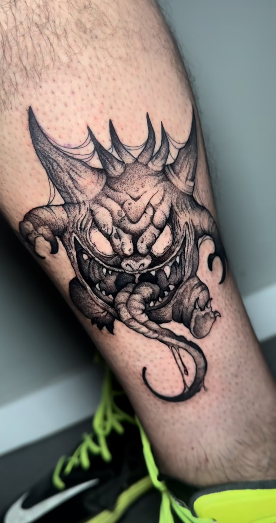 Tatuaje de monstruo estilo blackwork con sombreado intenso en la pierna.