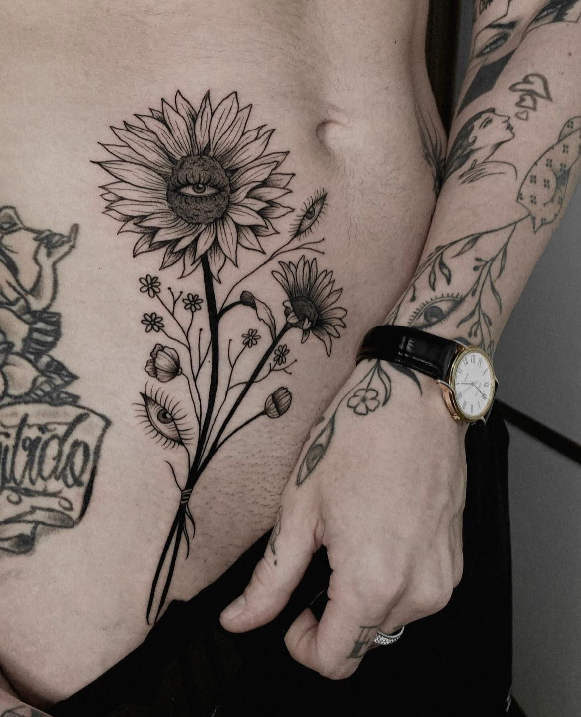Tatuaje blackwork de girasoles con ojos en la cadera.