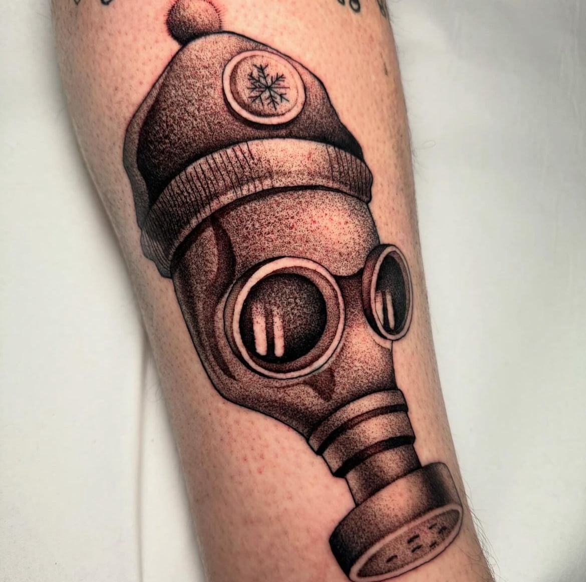 Tatuaje blackwork de máscara de gas en el brazo.