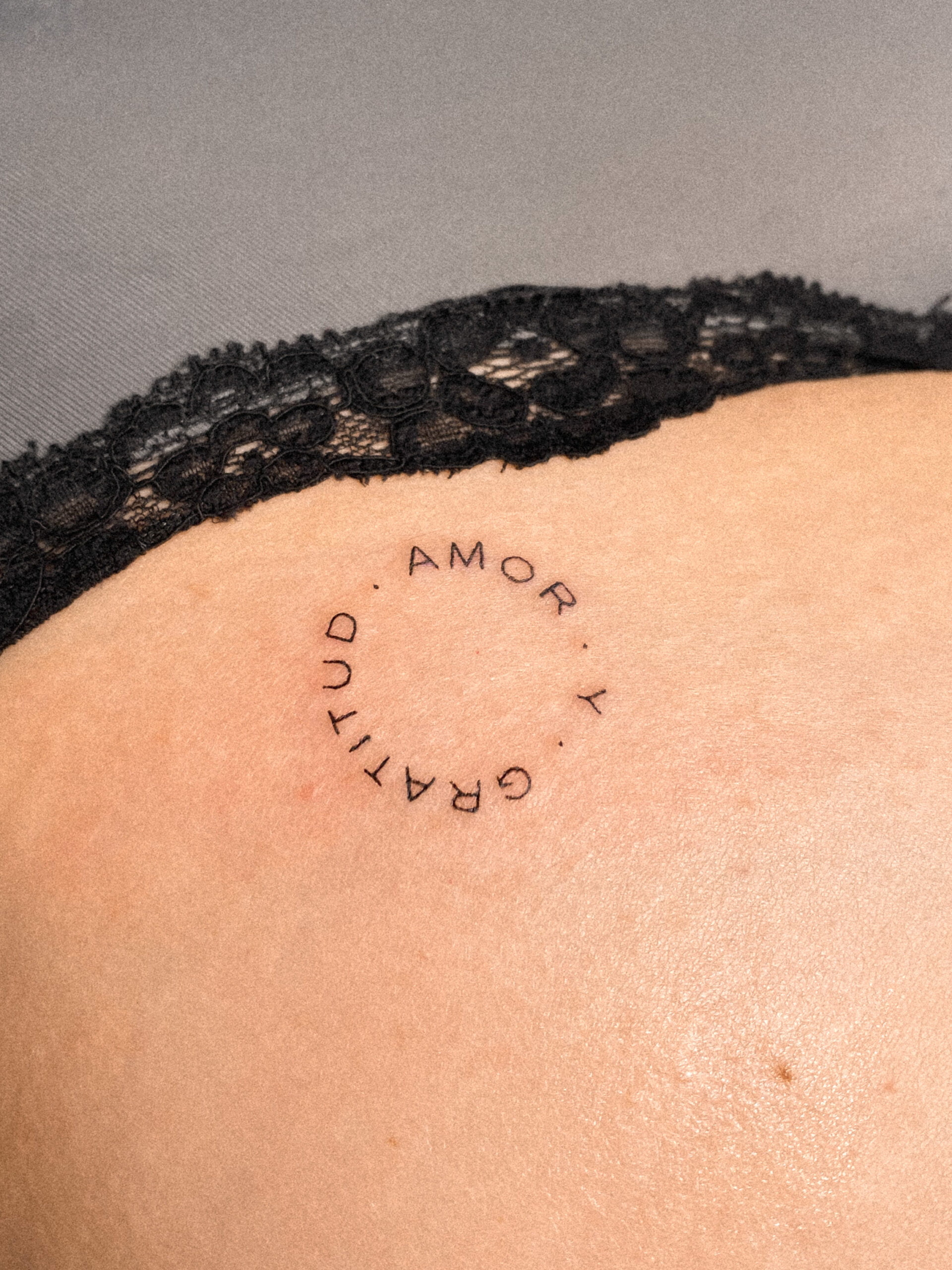 Tatuaje de palabras 'amor' y 'gratitud' en estilo minimalista en la cadera.
