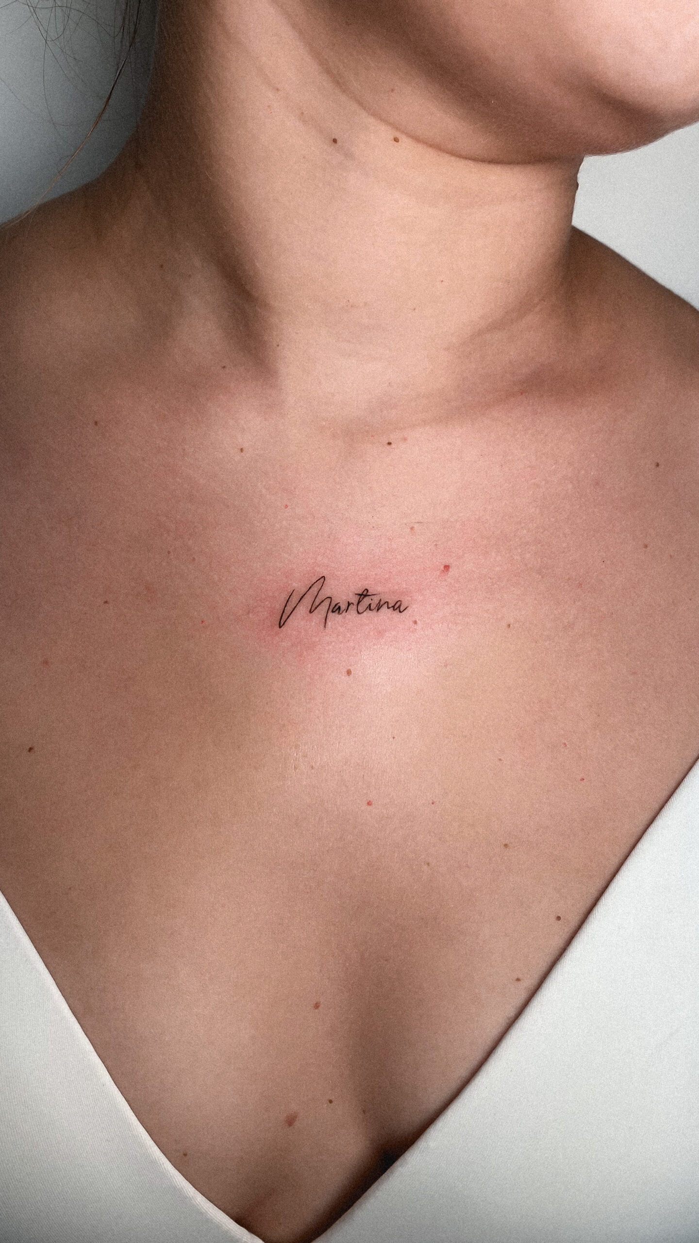 Tatuaje de un nombre en estilo fineline en la clavícula, transmitiendo elegancia.