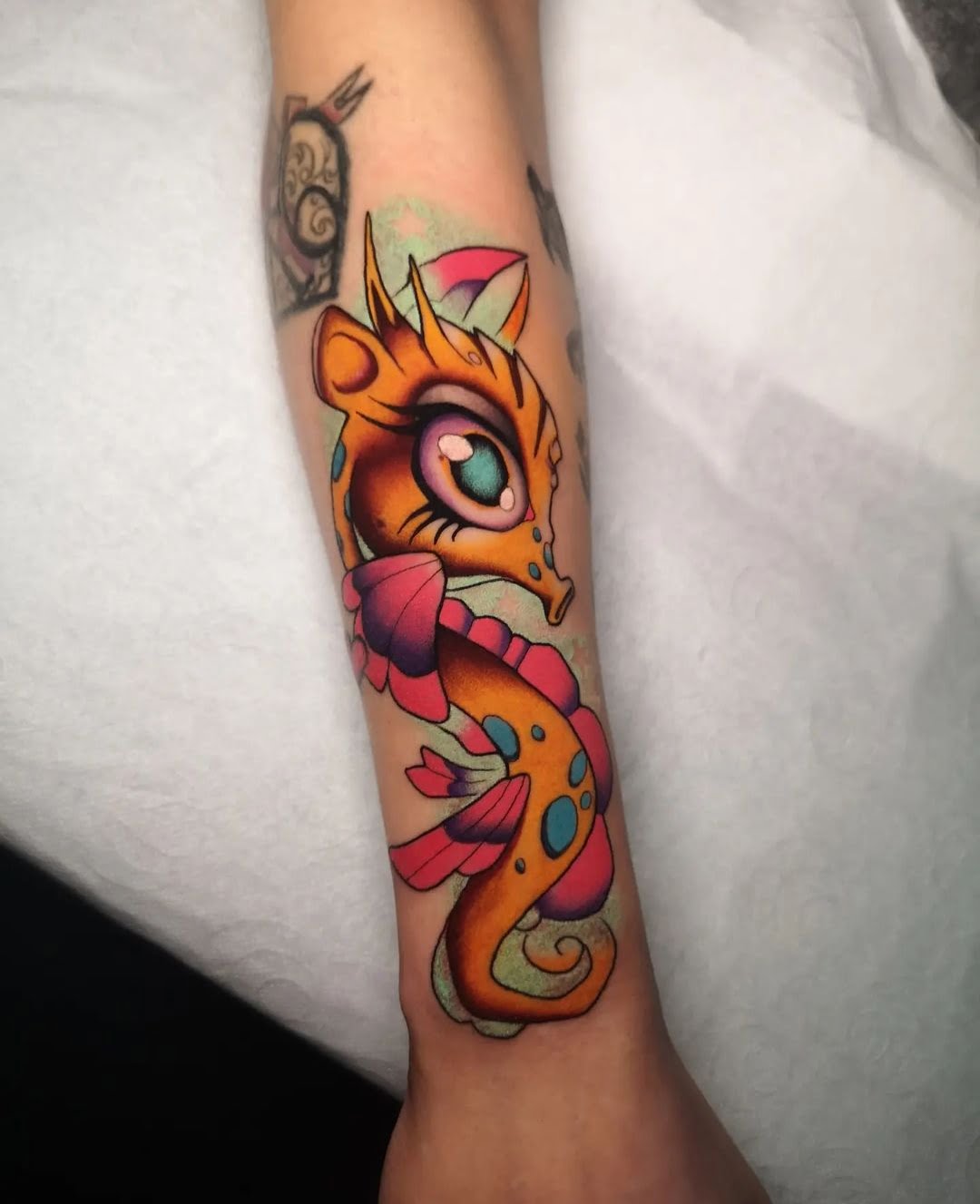 Tatuaje de un dragón colorido estilo neotradicional en el antebrazo, con tonos vibrantes que resaltan su mirada mística.