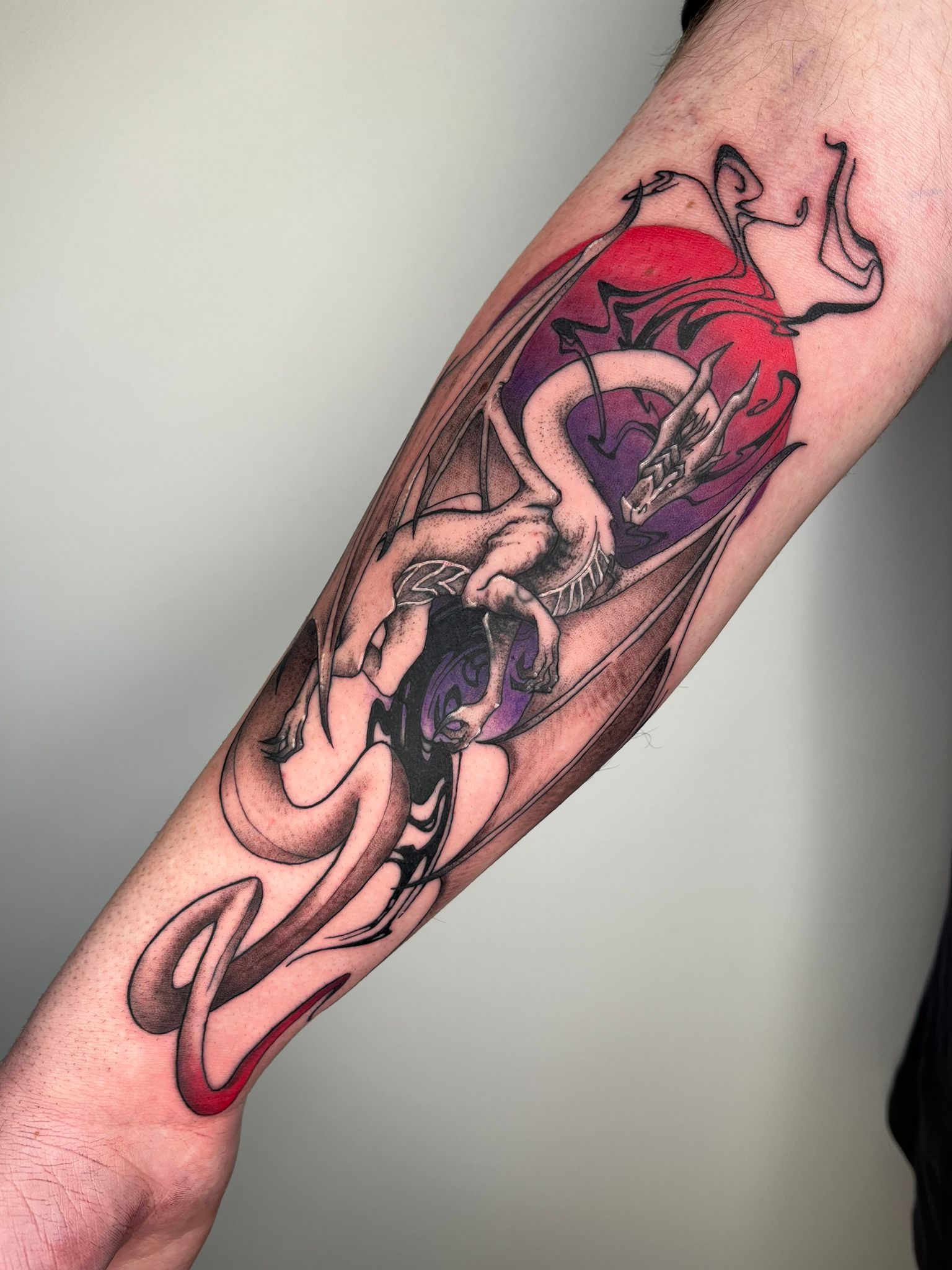 Tatuaje de dragón en estilo neotradicional con uso de color y líneas en antebrazo, evocando fuerza.