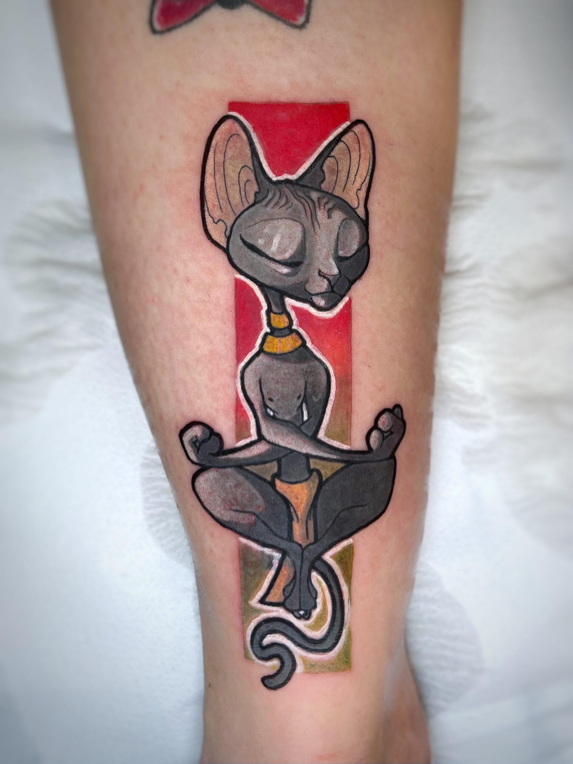 Tatuaje de un gato estilo cartoon meditando en el antebrazo con colores vibrantes.