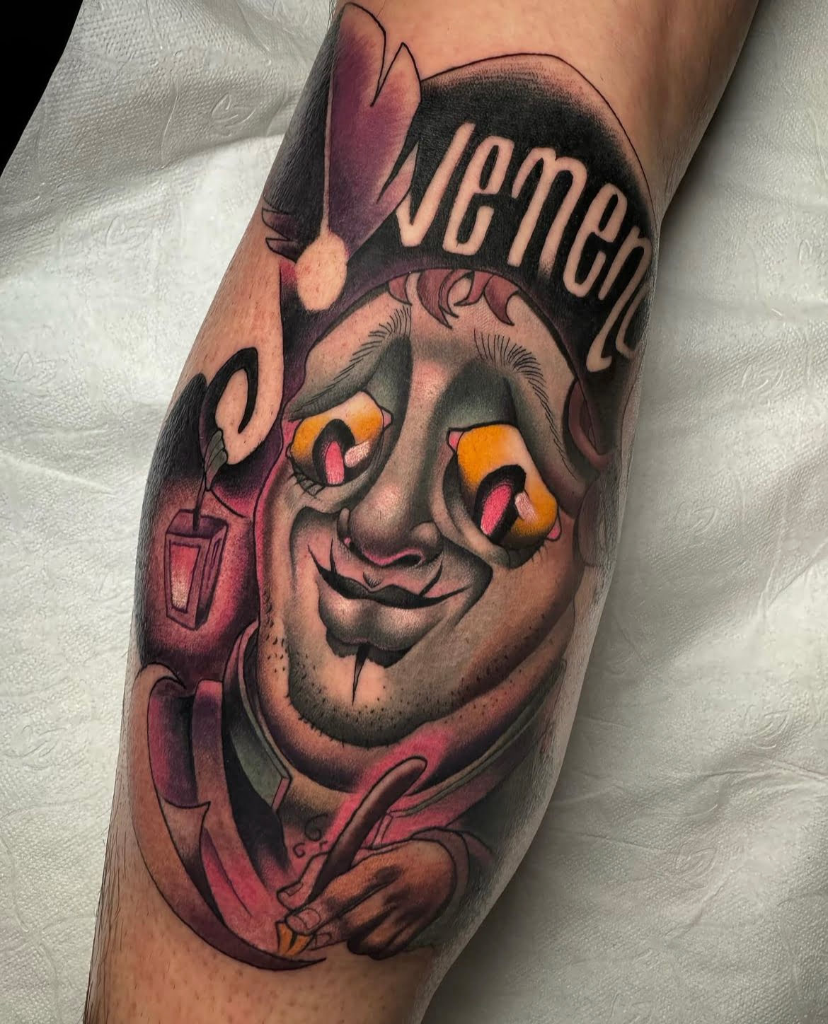 Tatuaje de payaso neotradicional en la pantorrilla con técnica de sombreado y colores vibrantes.