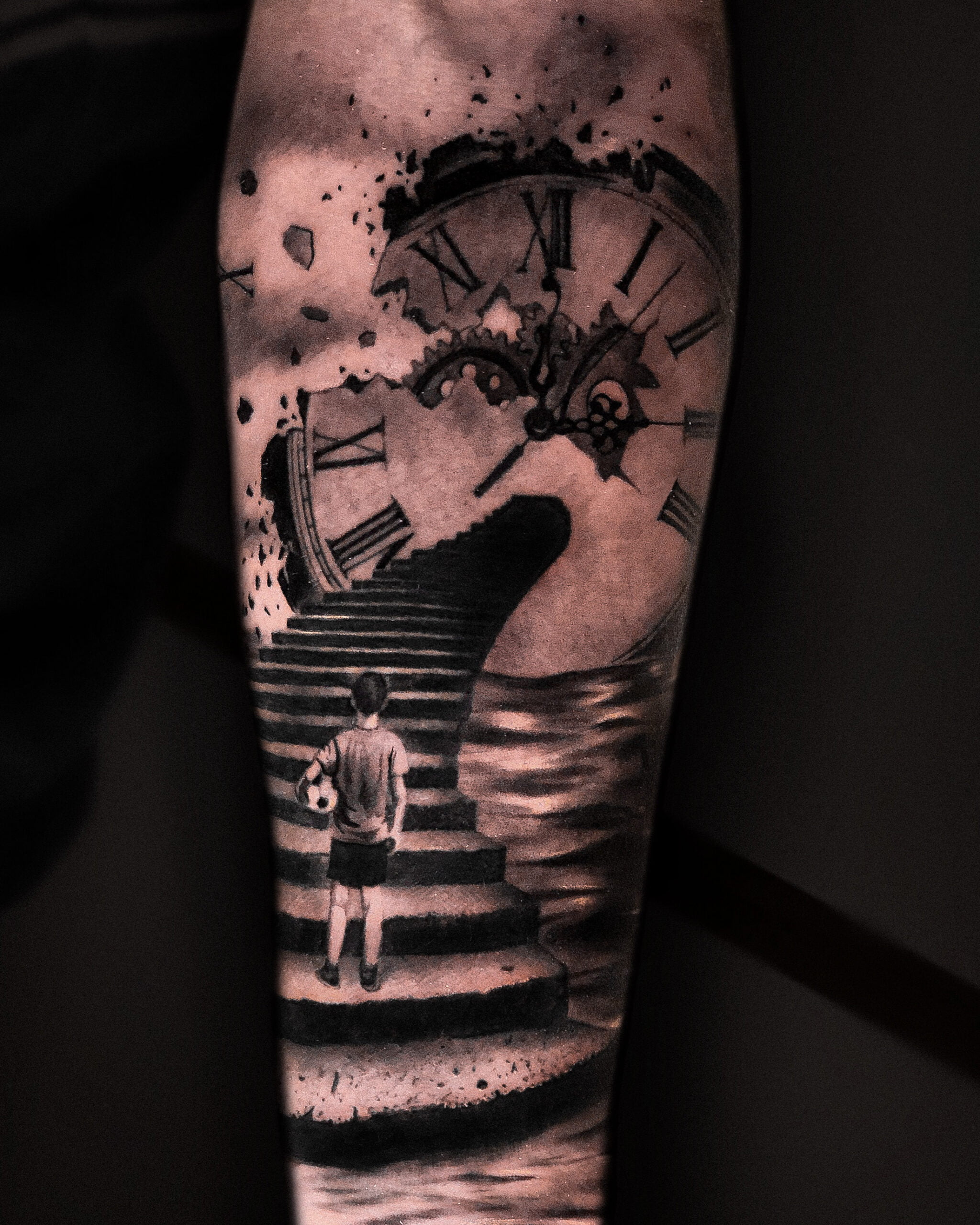 Tatuaje surrealista en blanco y negro de reloj roto y niño en brazo.