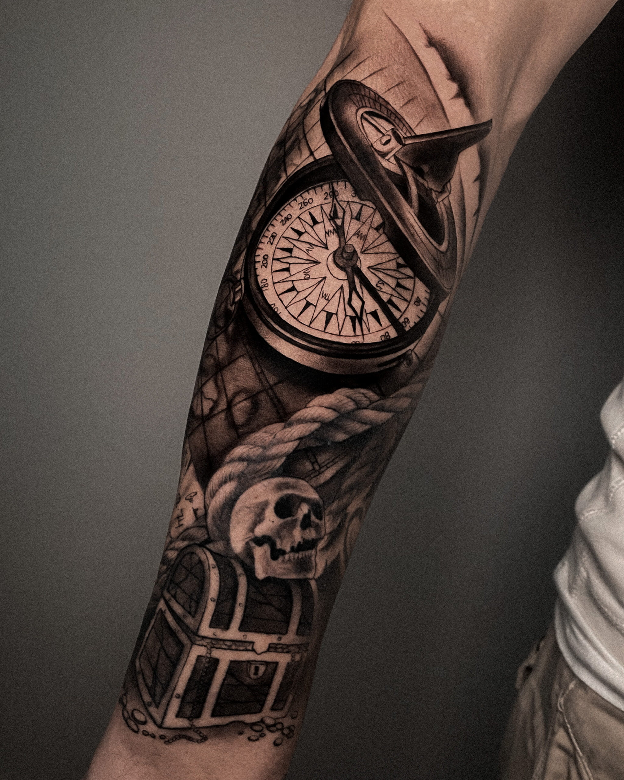 Tatuaje realista de cofre con calavera, mapa y brújula