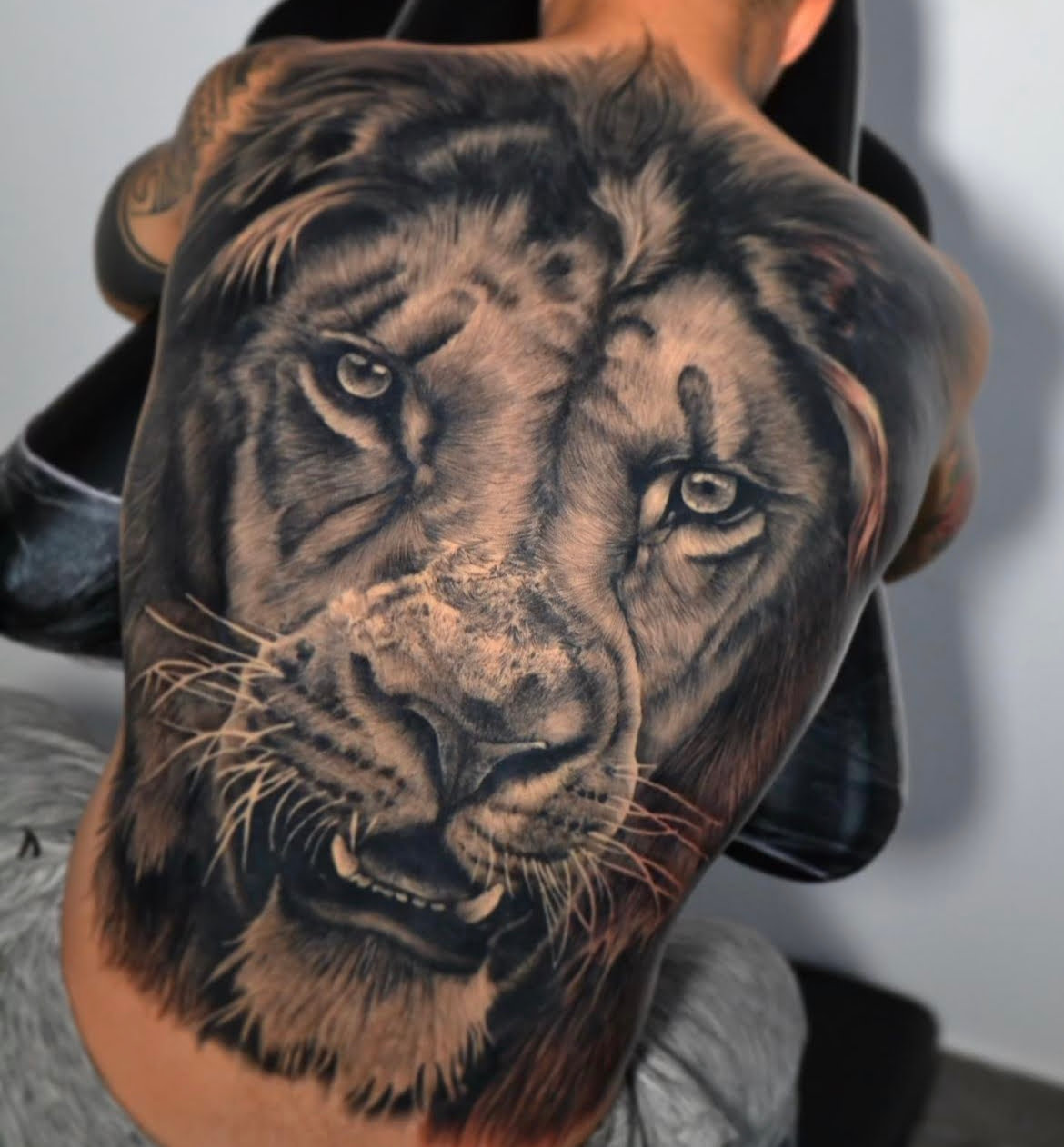 Tatuaje de un león realista en la espalda, estilo black and grey, que transmite fuerza.