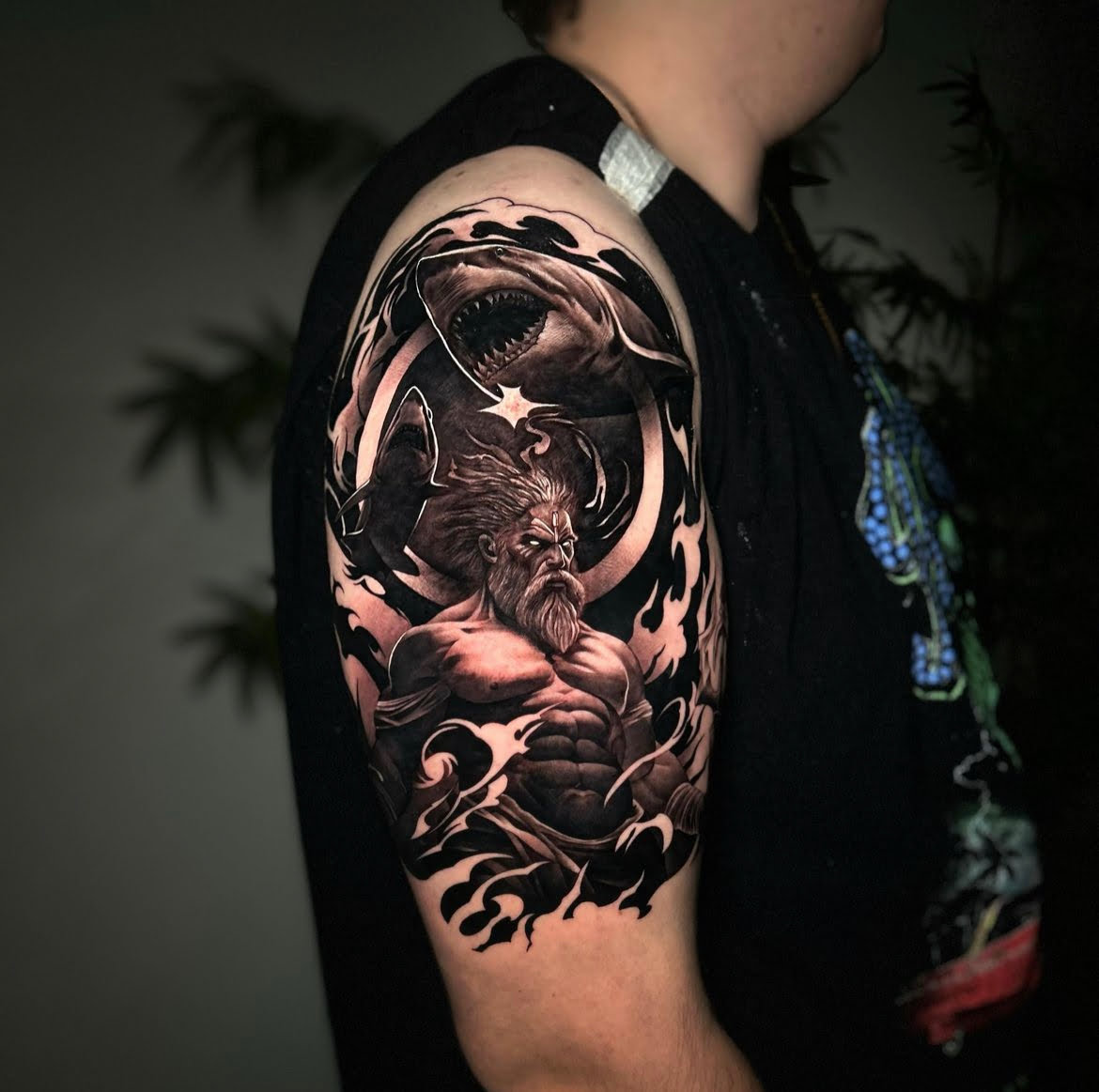Tatuaje realista de Poseidón con tiburones en el brazo.